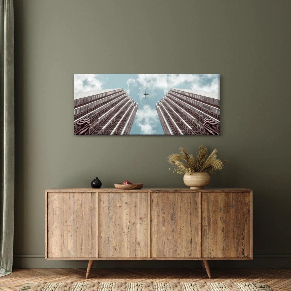 Obraz lietadla medzi budovami (120x50 cm)
