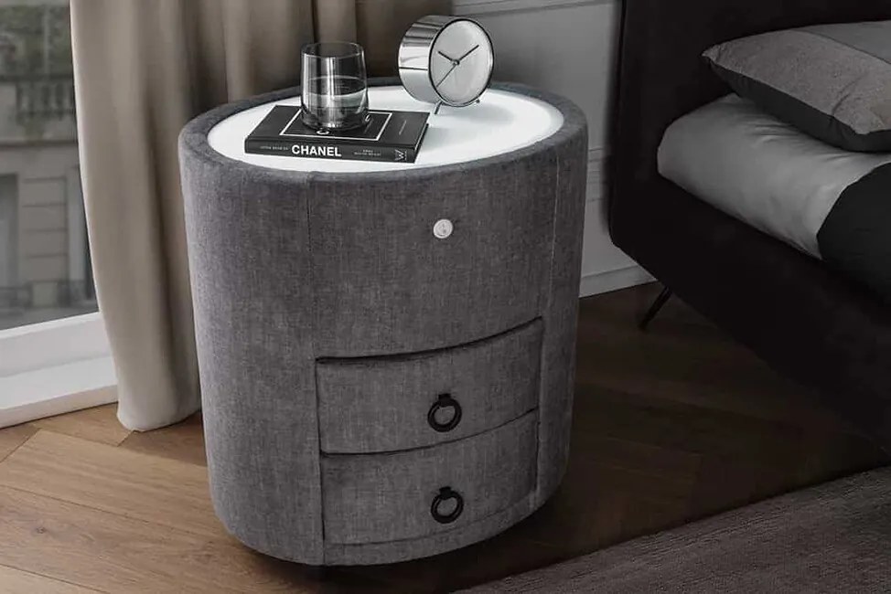 Oválny nočný stolík s integrovaným LED osvetlením Voiron šedý zamat 49cm
