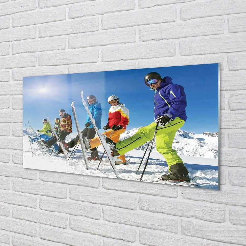 Obraz na skle Lyžiari zimné hory 140x70 cm