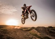 Fotografia Motocross rider performing high jump at sunset., skynesher