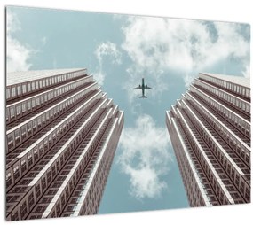 Sklenený obraz lietadla medzi budovami (70x50 cm)